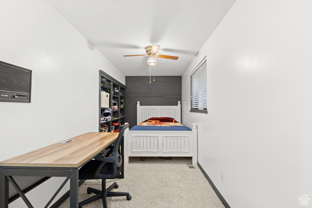 Carpeted bedroom with an office area and ceiling fan