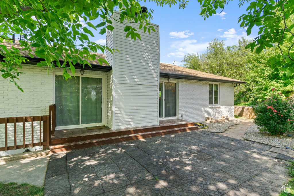 Back of property featuring a chimney, brick siding, and a patio area