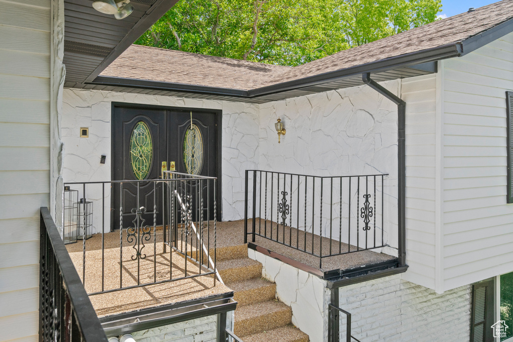 View of exterior entry with a shingled roof