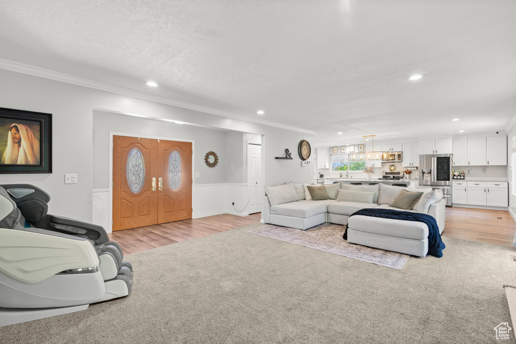 Living room featuring recessed lighting, ornamental molding, and light wood-style floors