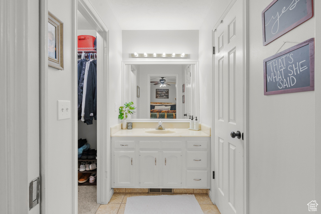 Bathroom featuring vanity, ceiling fan, and a walk in closet