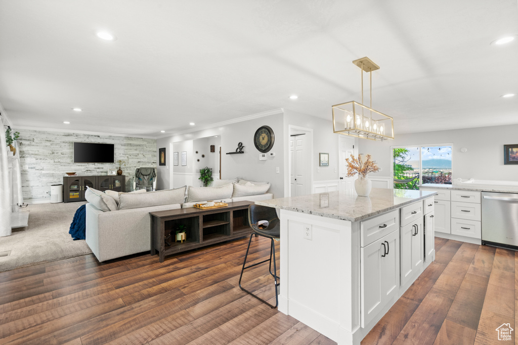 Kitchen featuring stainless steel dishwasher, recessed lighting, white cabinetry, light stone countertops, and a center island