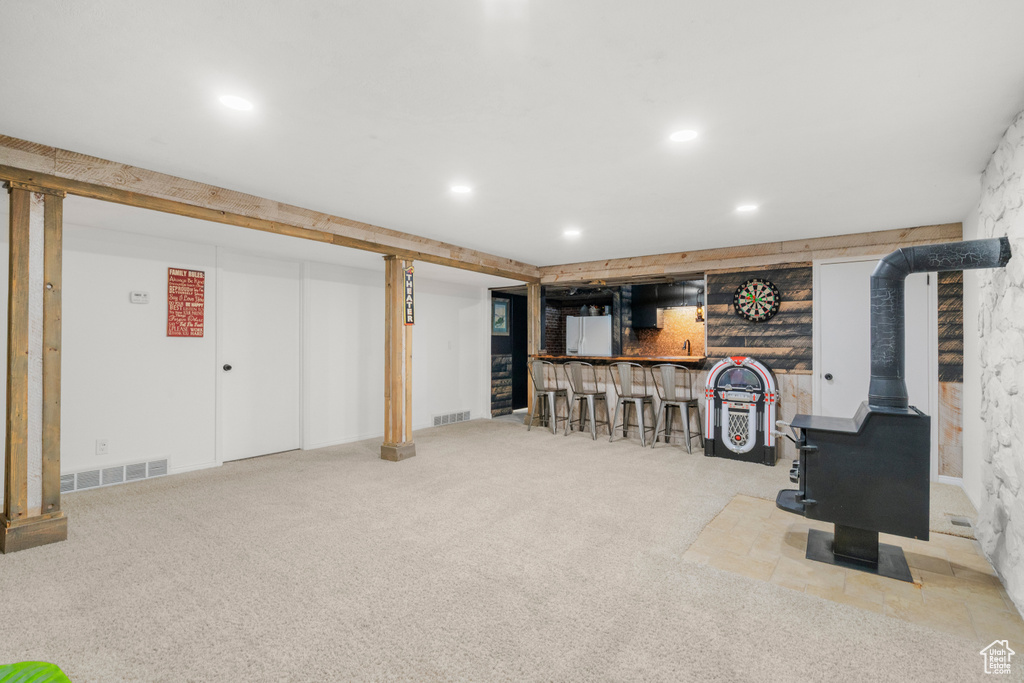 Finished below grade area with carpet, bar area, a wood stove, and recessed lighting