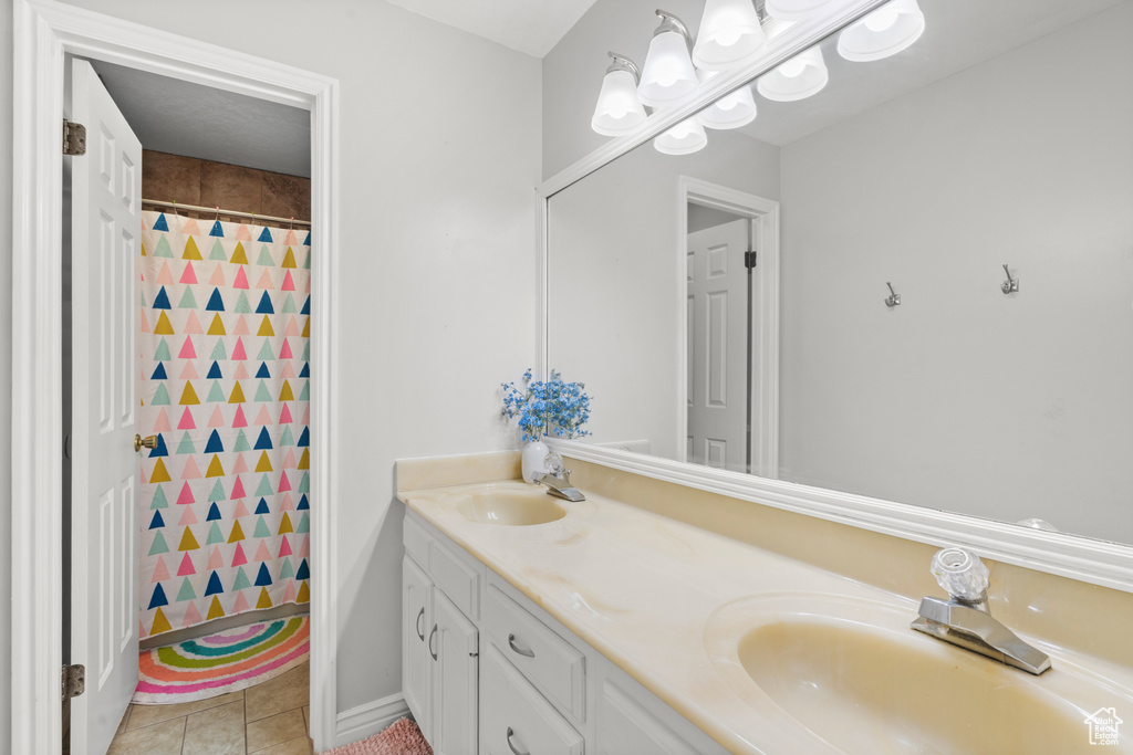 Full bathroom with double vanity, tile patterned flooring, and a shower with curtain