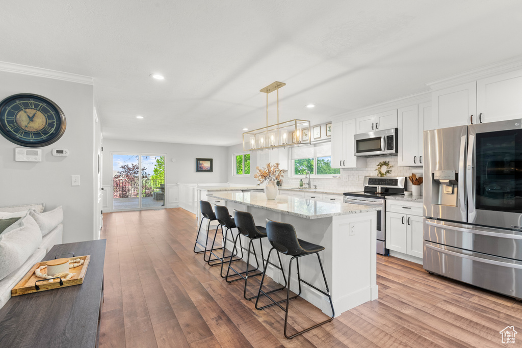 Kitchen featuring appliances with stainless steel finishes, a breakfast bar area, white cabinets, a kitchen island, and recessed lighting