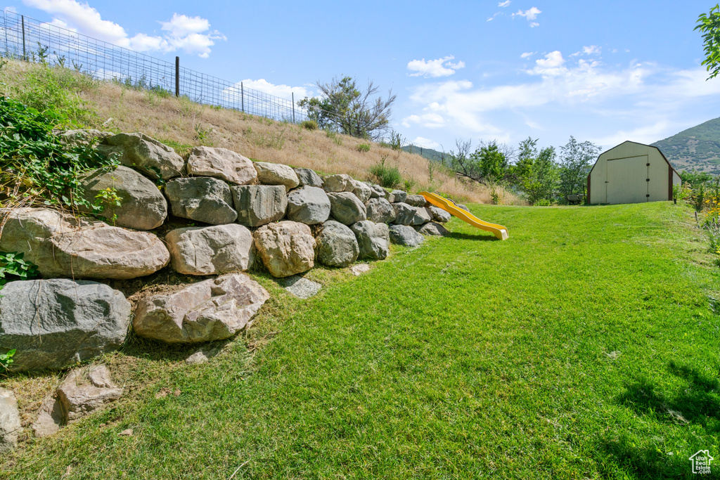 View of yard featuring a storage shed and a playground