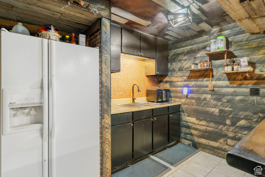 Kitchen featuring white refrigerator with ice dispenser, light tile patterned floors, and light countertops