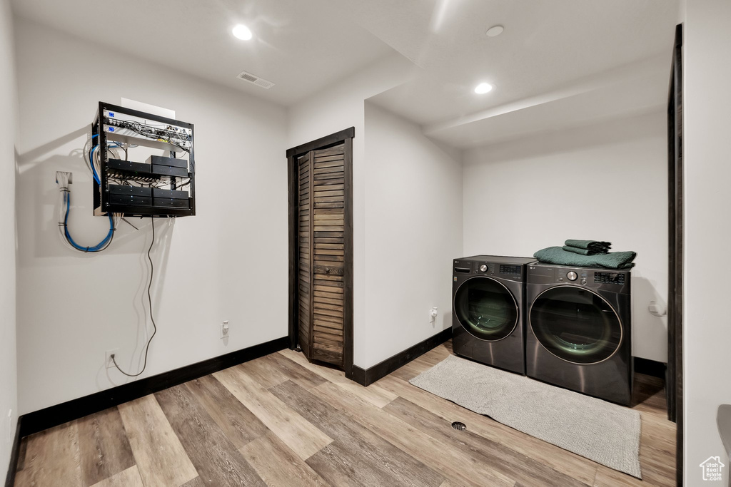 Laundry area featuring separate washer and dryer, wood finished floors, and recessed lighting