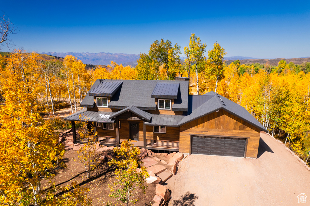 Chalet / cabin featuring a forest view, a porch, a standing seam roof, and an attached garage