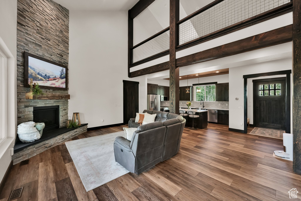 Living room with high vaulted ceiling, a stone fireplace, and dark wood-type flooring
