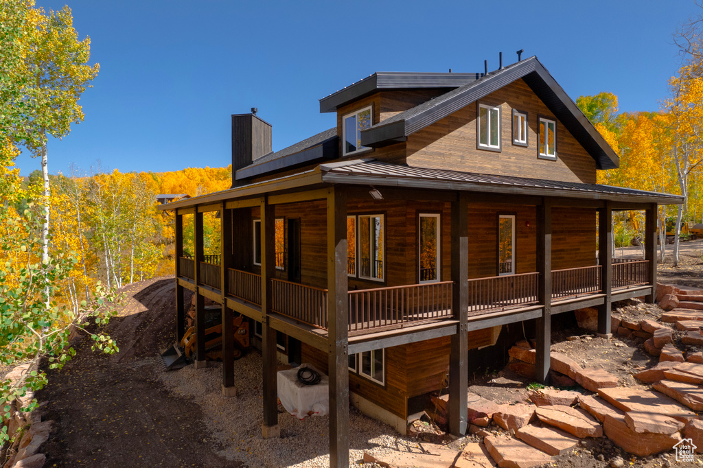 Back of property featuring a chimney, a metal roof, and a standing seam roof