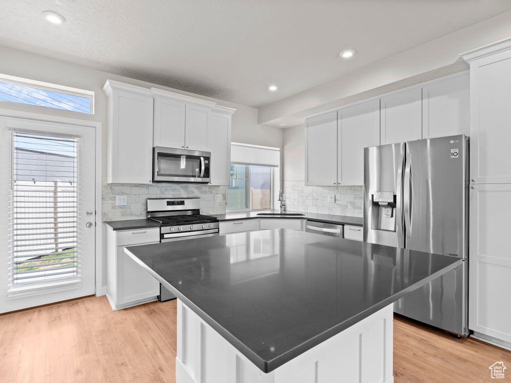 Kitchen featuring appliances with stainless steel finishes, dark countertops, healthy amount of natural light, backsplash, and recessed lighting