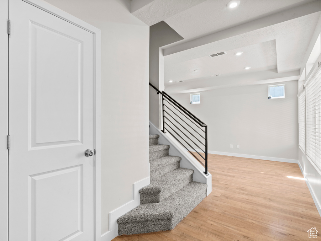 Stairway featuring wood finished floors and recessed lighting