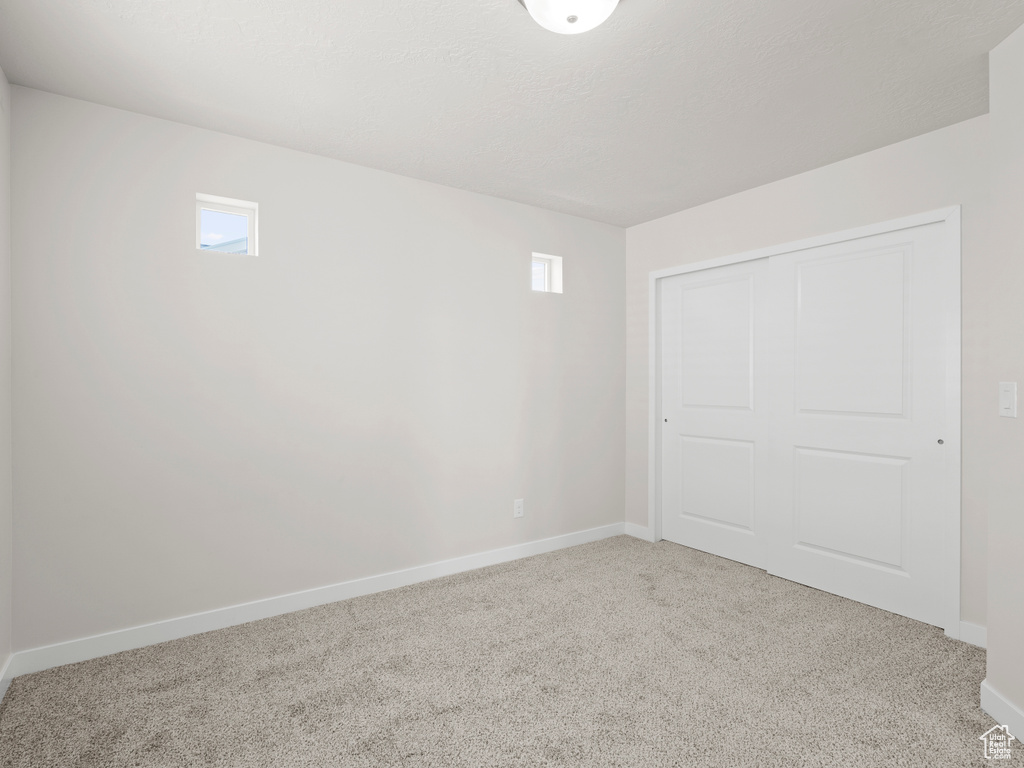 Unfurnished bedroom with carpet floors, a closet, and multiple windows