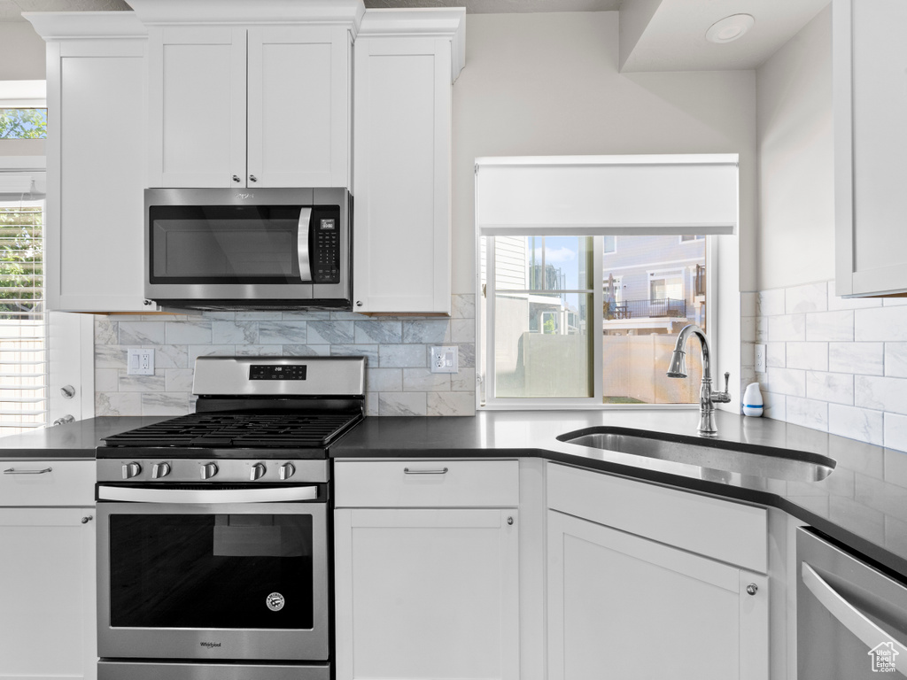 Kitchen featuring stainless steel appliances, dark countertops, and white cabinets