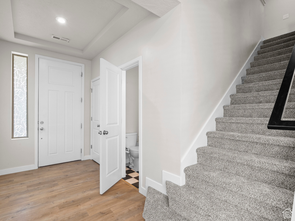 Entrance foyer featuring stairway, light wood-type flooring, and a tray ceiling