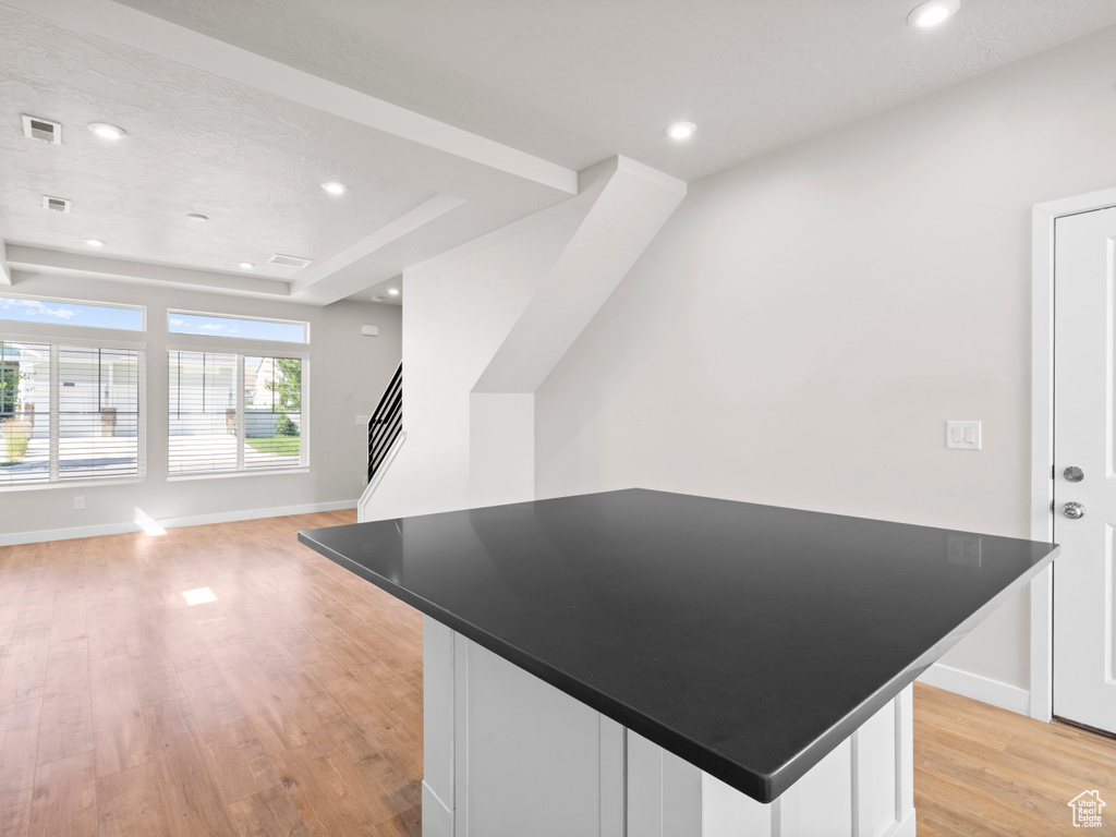 Kitchen featuring light wood finished floors, open floor plan, dark countertops, white cabinetry, and recessed lighting