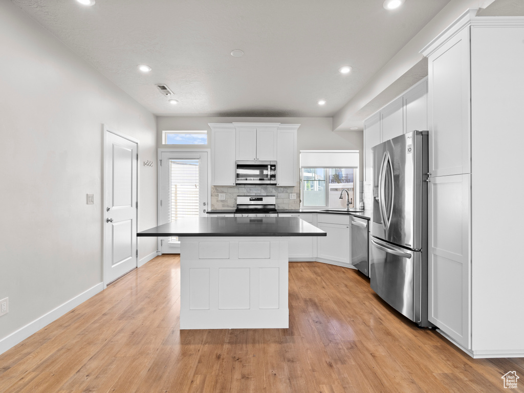 Kitchen with appliances with stainless steel finishes, decorative backsplash, a center island, white cabinets, and recessed lighting