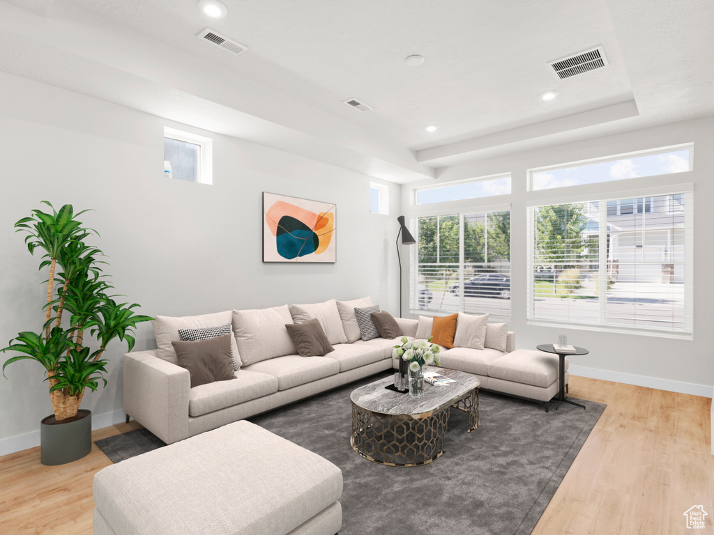 Living area with wood finished floors, plenty of natural light, a raised ceiling, and recessed lighting