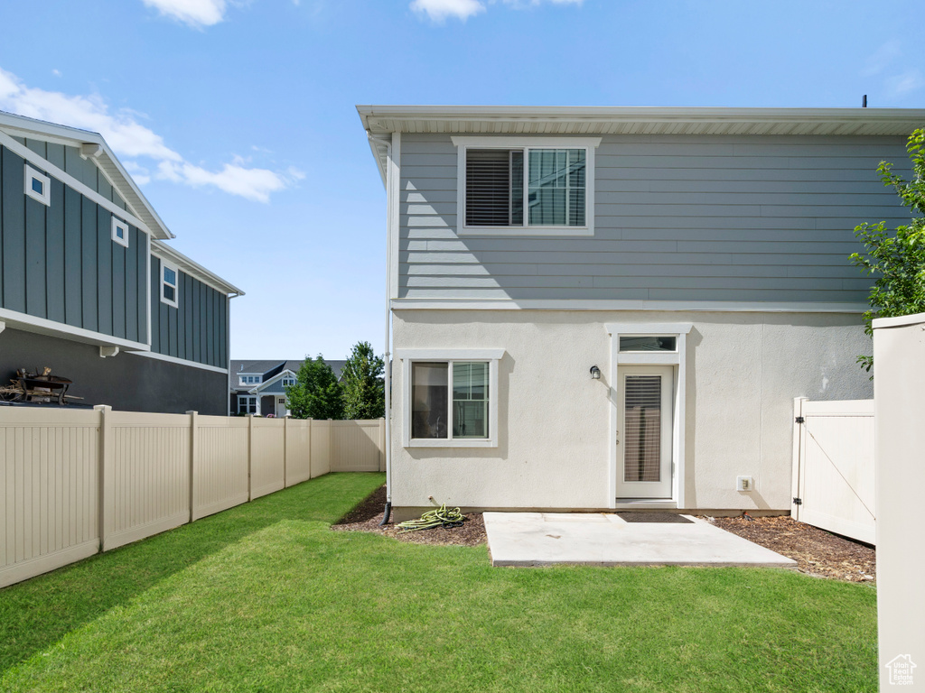 Rear view of property with a fenced backyard, a patio area, and stucco siding
