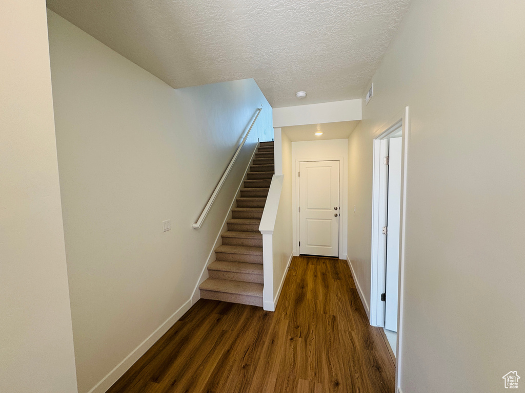Staircase featuring wood finished floors and a textured ceiling