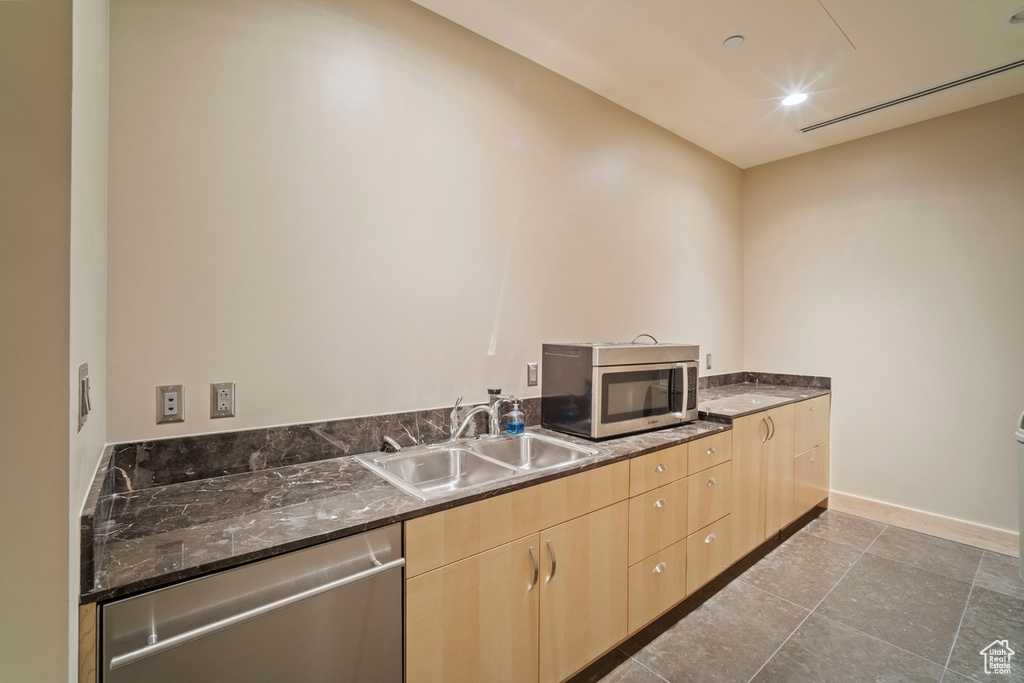 Kitchen with appliances with stainless steel finishes, light brown cabinetry, recessed lighting, and dark stone countertops