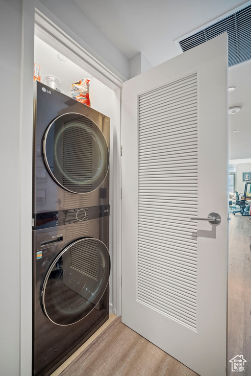 Laundry area featuring stacked washing machine and dryer and wood finished floors