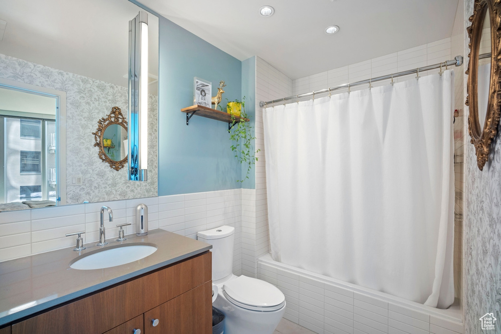 Bathroom with vanity, tile walls, shower / bath combination with curtain, and wainscoting