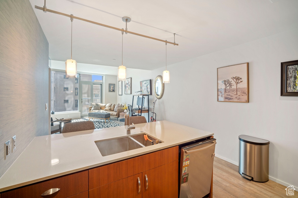 Kitchen featuring dishwasher, light wood-style floors, light countertops, open floor plan, and brown cabinets