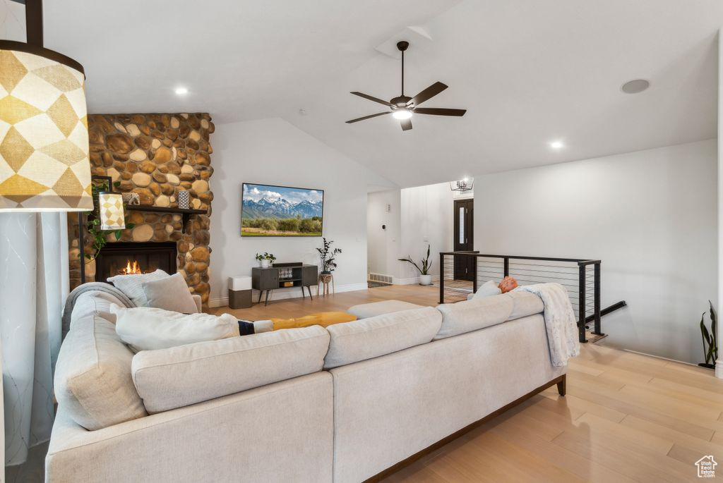 Living area with a ceiling fan, wood finished floors, lofted ceiling, and a fireplace
