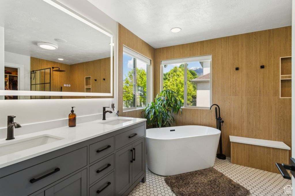 Bathroom featuring a freestanding bath, double vanity, wooden walls, and a closet