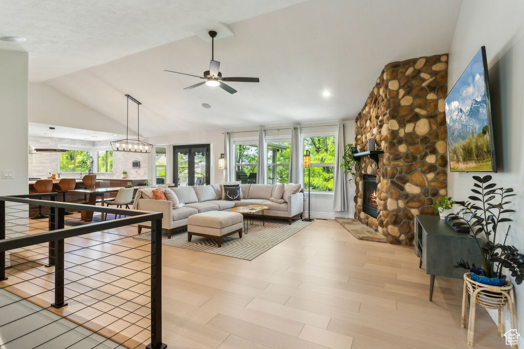Living area with vaulted ceiling, a ceiling fan, a fireplace, and plenty of natural light