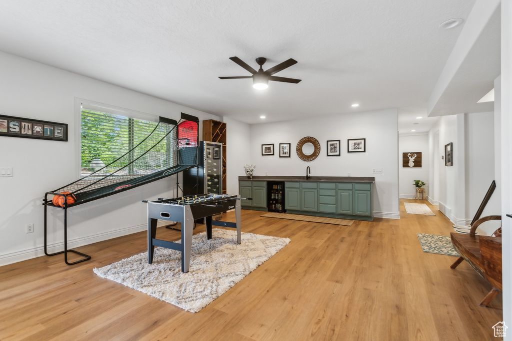 Living area featuring bar with sink, beverage cooler, ceiling fan, light wood-style floors, and recessed lighting