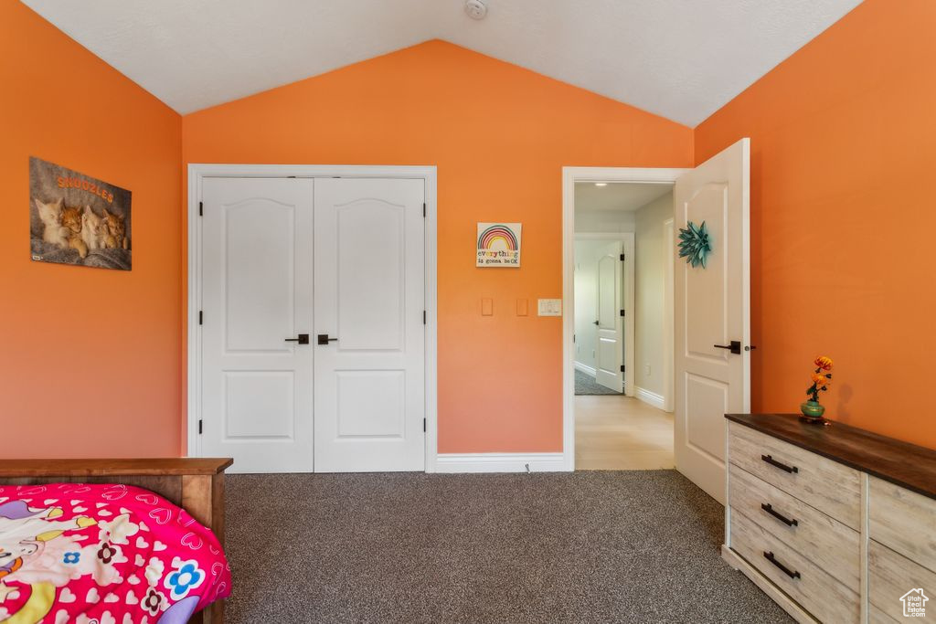 Carpeted bedroom featuring lofted ceiling and a closet