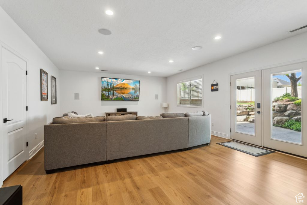Living room with french doors, light wood-type flooring, and recessed lighting
