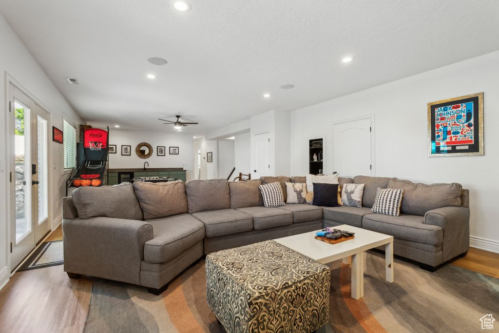 Living room featuring light wood-style flooring, recessed lighting, a ceiling fan, and bar