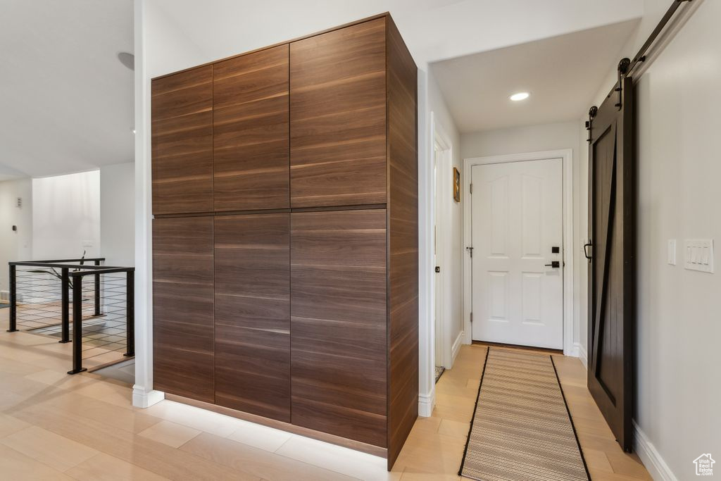 Hall featuring a barn door, recessed lighting, and an upstairs landing