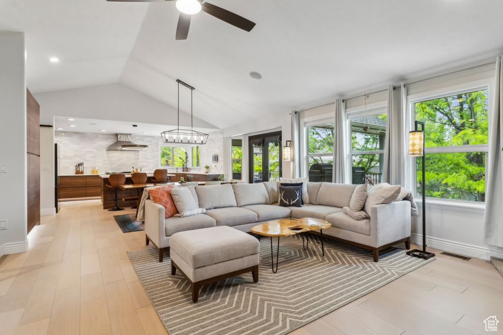 Living room featuring light wood-style floors, vaulted ceiling, and ceiling fan