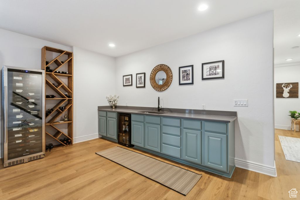 Indoor wet bar with beverage cooler, light wood-style floors, and recessed lighting