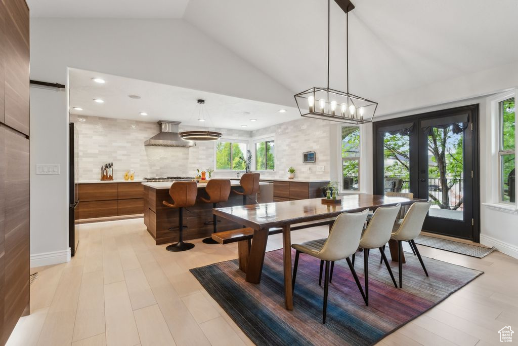 Dining space with lofted ceiling, french doors, light wood-style flooring, and recessed lighting