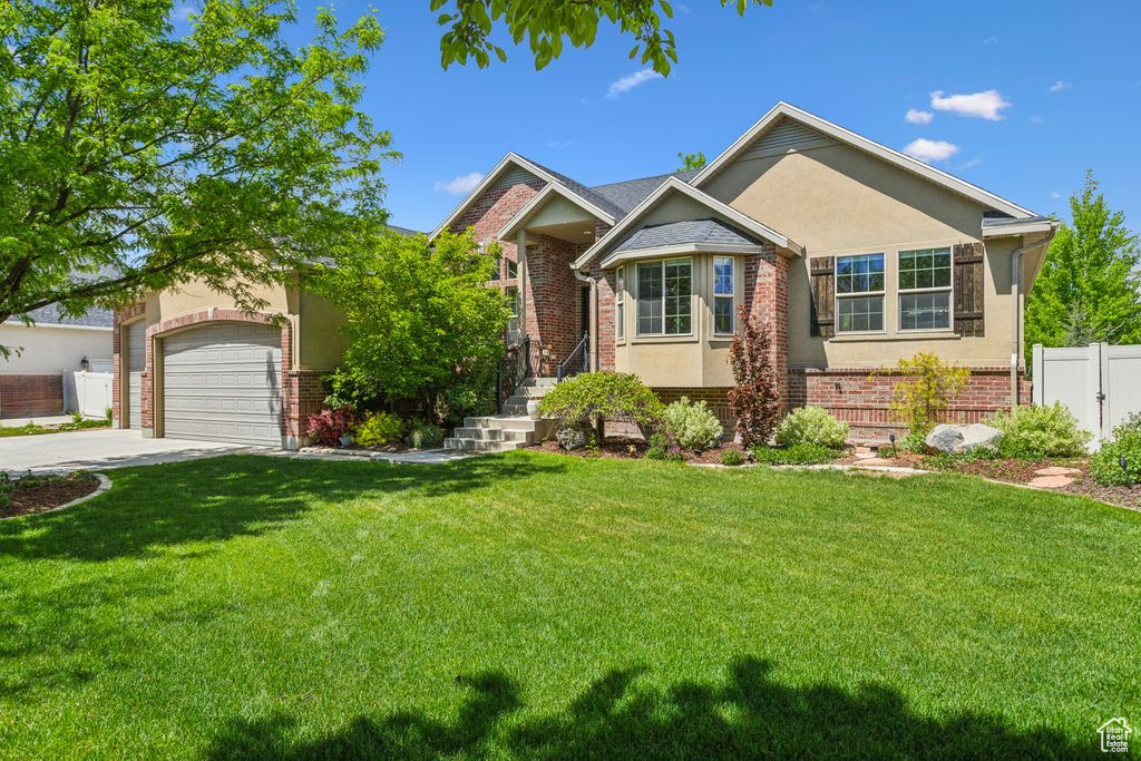 View of front of home featuring brick siding, concrete driveway, stucco siding, and a garage