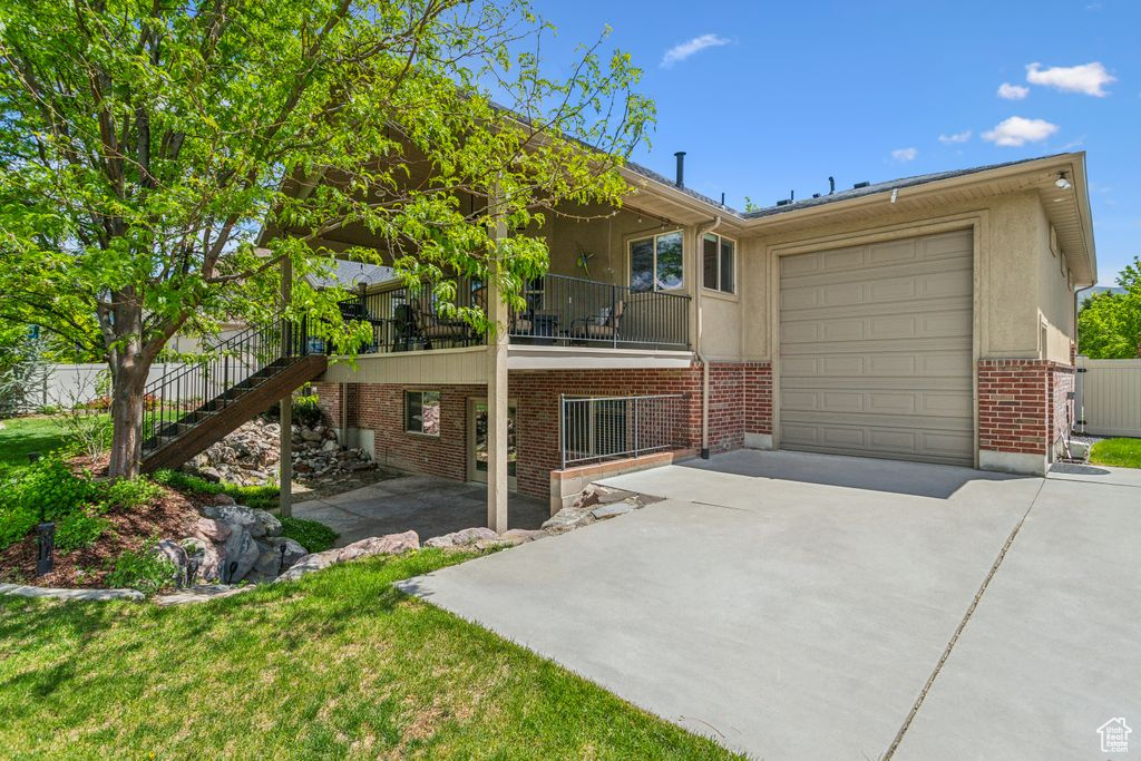 View of front facade featuring driveway, brick siding, an attached garage, stairway, and a front lawn
