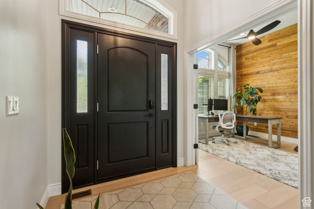 Foyer entrance featuring wooden walls, light wood-style floors, and a ceiling fan