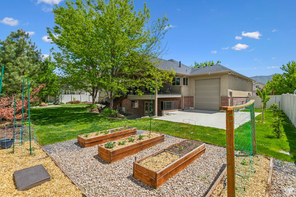 View of yard featuring a vegetable garden, a garage, and a patio area