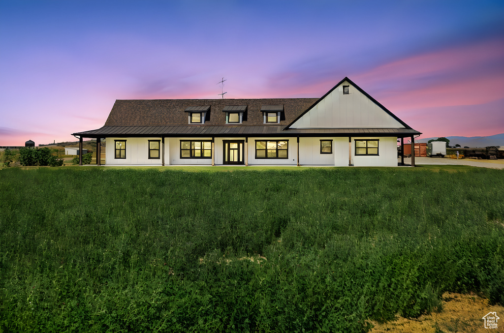 Back of property at dusk featuring a yard and a metal roof