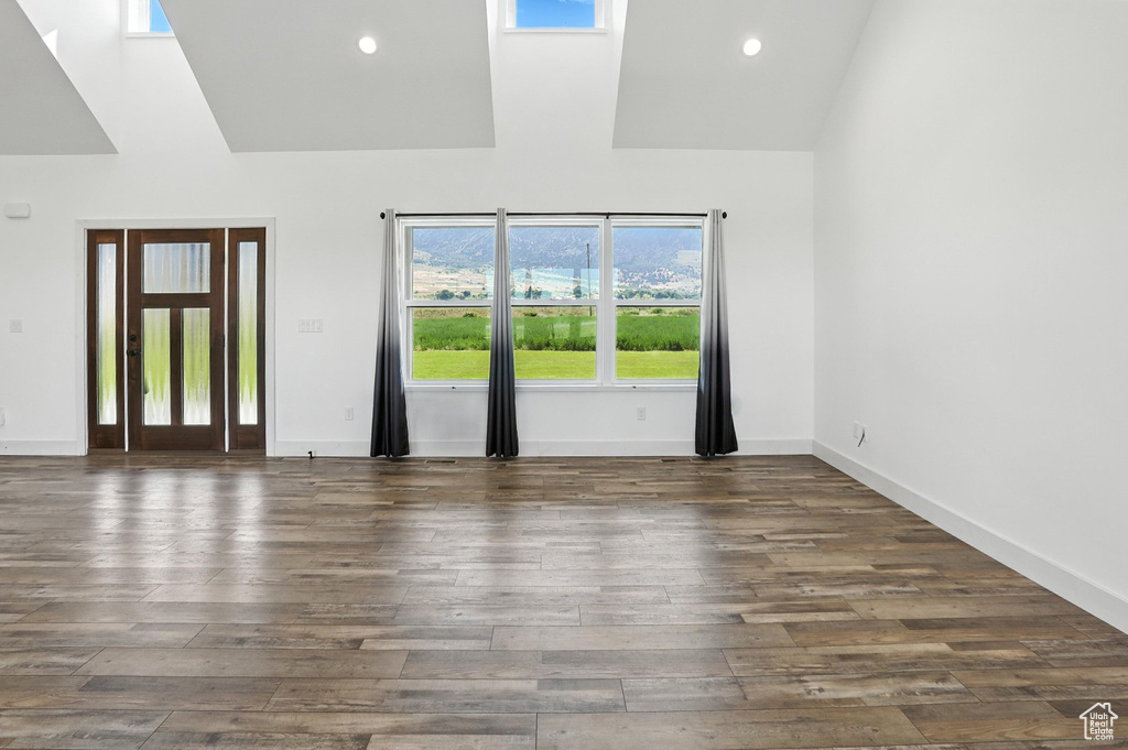 Spare room with wood finished floors, high vaulted ceiling, and recessed lighting