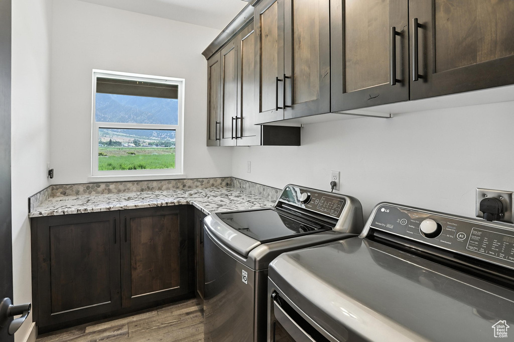 Washroom with cabinet space, washer and clothes dryer, and light wood-type flooring