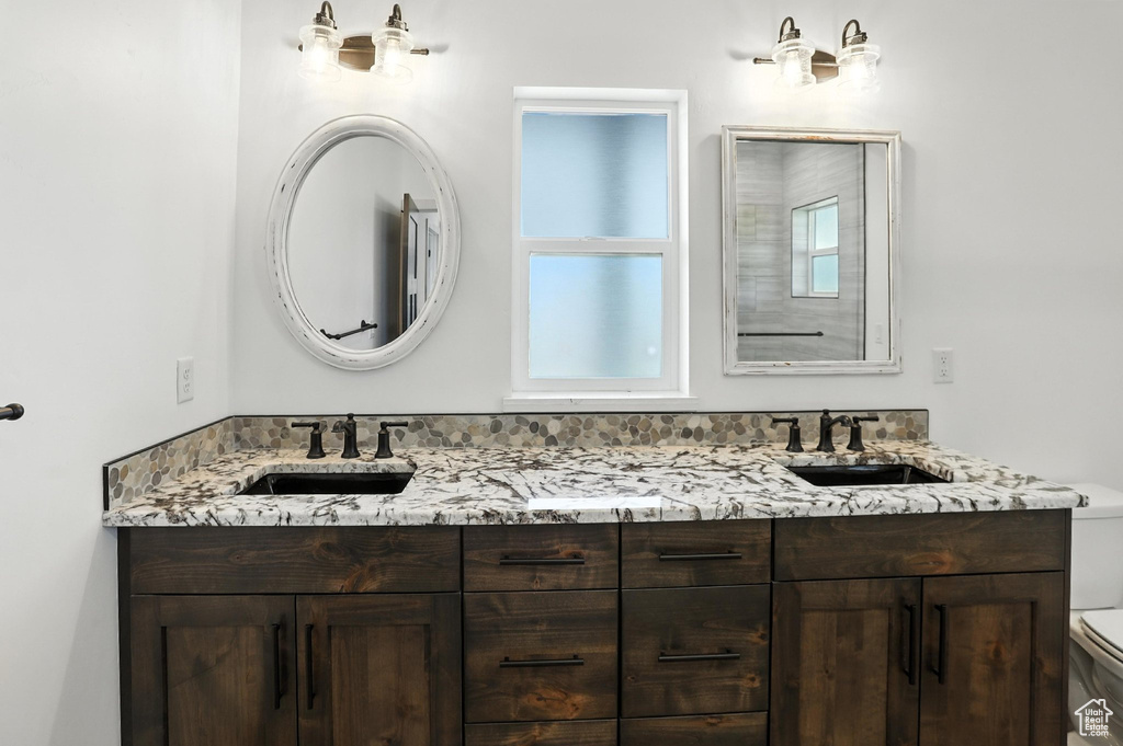 Full bath featuring toilet and double vanity
