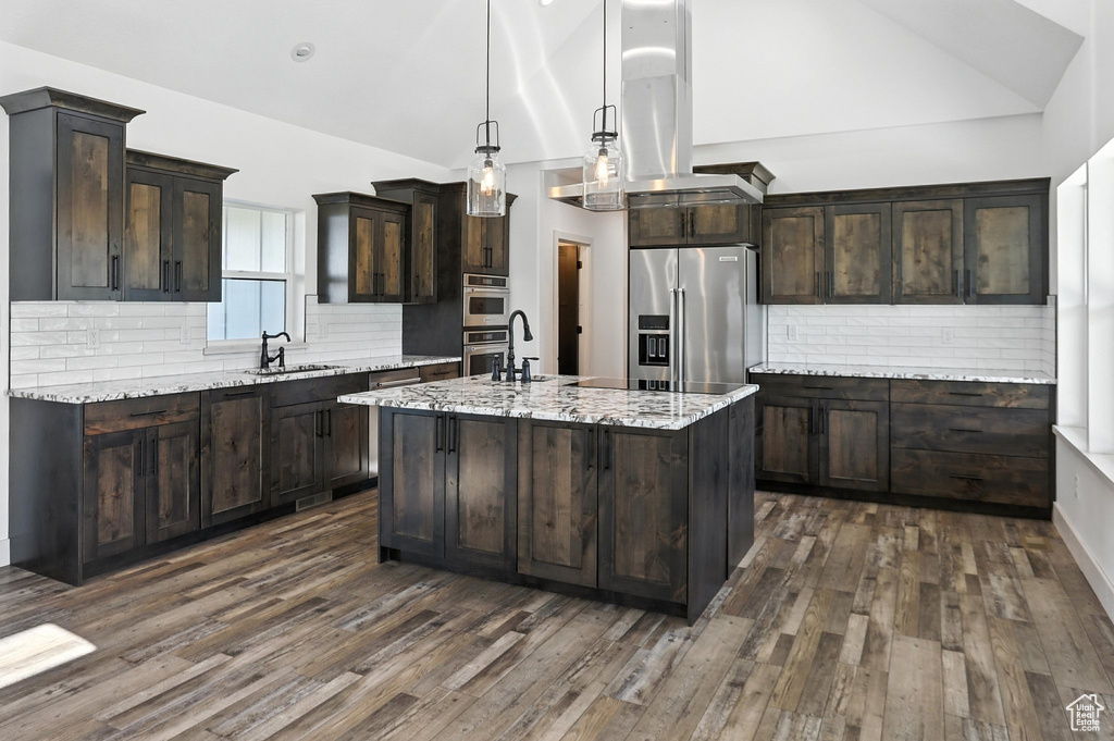 Kitchen featuring appliances with stainless steel finishes, vaulted ceiling, dark brown cabinets, tasteful backsplash, and dark wood-type flooring