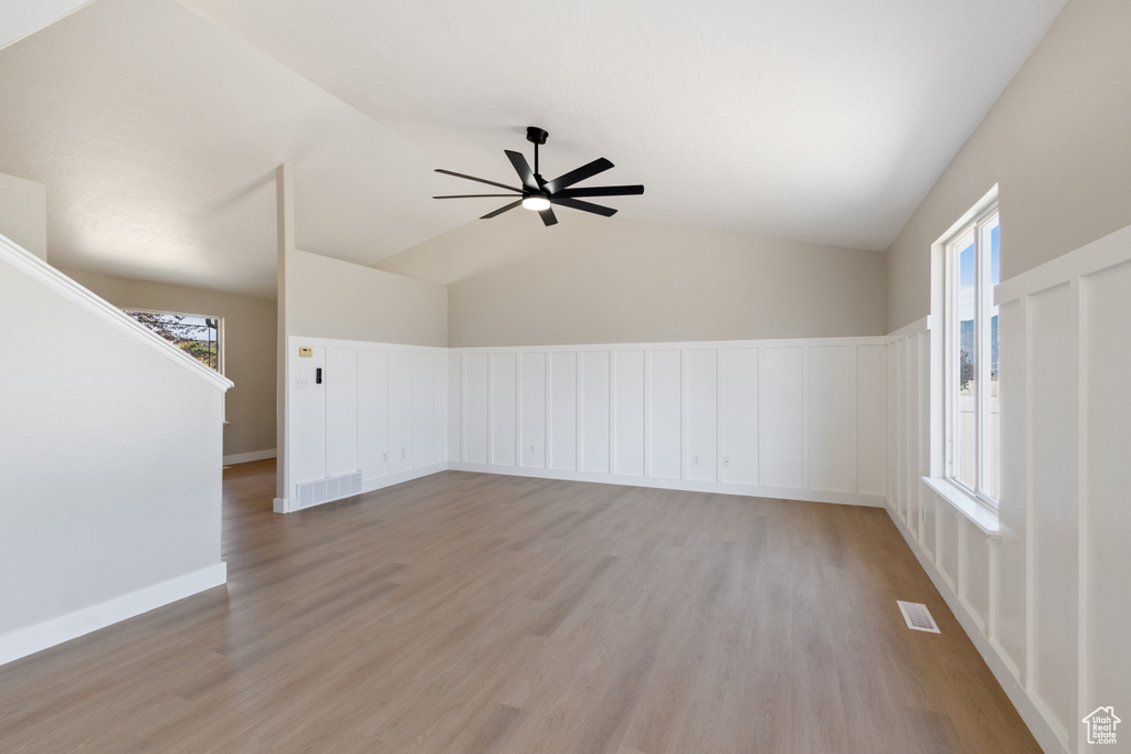 Spare room featuring light wood-type flooring, ceiling fan, and lofted ceiling
